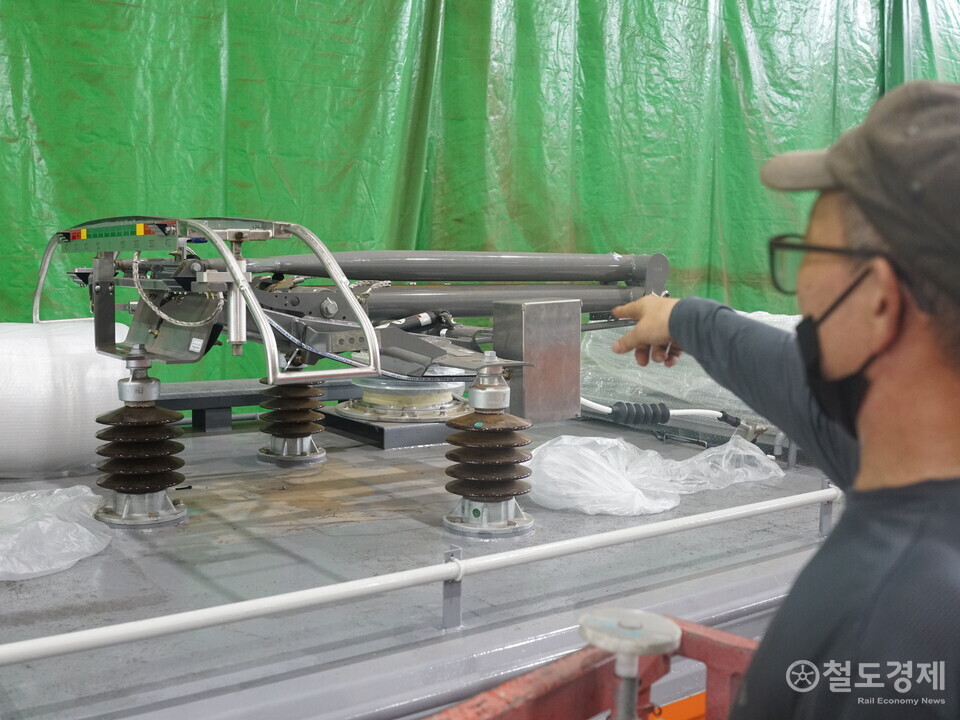 현장 작업자가 센서가 부착된 검사 장비 시스템을 가리키고 있다. / 철도경제